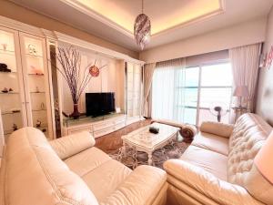 a living room with a white couch and a tv at Luxury Seaview Family Suite at Straits Quay in Tanjong Tokong