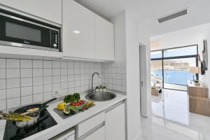 biała kuchnia ze zlewem i mikrofalówką w obiekcie Beach Apartment Playa del Cura 4 w mieście Playa del Cura