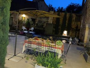 a patio with a table and an umbrella at Le Clos de Peyruzel, Daglan in Daglan