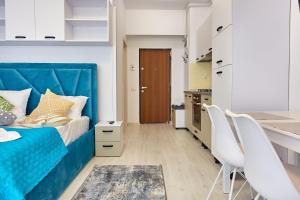 a bedroom with a blue bed and two white chairs at Apartamente Tomis Villa 2 in Năvodari