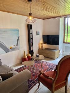 a living room with a couch and a tv at Le Petit Four à Pain in Neuvicq-Montguyon