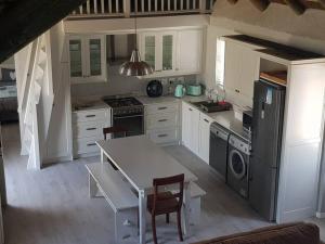 een keuken met witte kasten en een tafel met stoelen bij Ocean Breeze Cottage, Cape Agulhas in Struisbaai