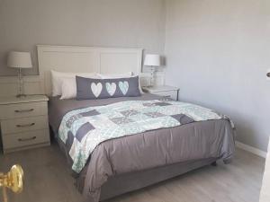 een slaapkamer met een groot bed met twee nachtkastjes bij Ocean Breeze Cottage, Cape Agulhas in Struisbaai