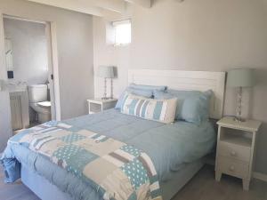 een slaapkamer met een bed en 2 tafels met lampen bij Ocean Breeze Cottage, Cape Agulhas in Struisbaai +41 foto's
