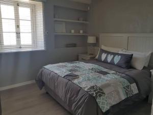 een slaapkamer met een groot bed in een kamer bij Ocean Breeze Cottage, Cape Agulhas in Struisbaai