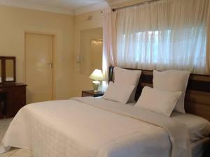 a bedroom with a large white bed with a window at Guesthouse with green garden and pool - 2102 in Harare