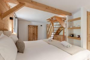 a bedroom with a large white bed with wooden ceilings at La Bastide - Grand chalet privé - Quartier calme in Les Houches