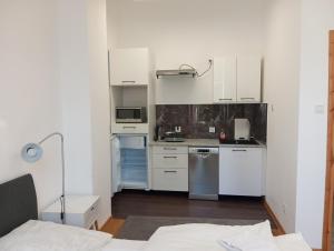 a kitchen with white cabinets and a bed in a room at Mirabella 1 in Kołobrzeg