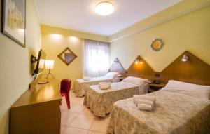 a hotel room with three beds and a television at Bilo 4 in Lido di Mondello
