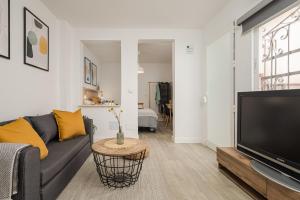 a living room with a couch and a tv at Nordik Rooms Urban - Trinidad "Mariehamn" in Málaga