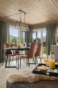 a dining room with a table and chairs and windows at Moderne hytte på Fjellsætra med Jacuzzi in Sykkylven