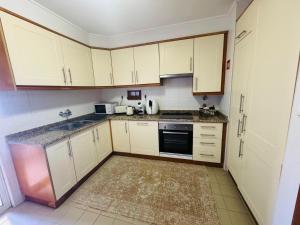 a small kitchen with white cabinets and a sink at Azor International Apartment II in Ponta Delgada