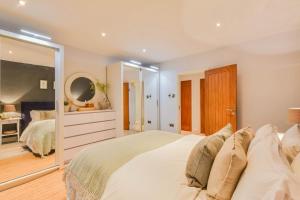 a bedroom with a large white bed and a mirror at The Hideaway @ Flagham Cottage. in Malmesbury