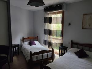 a bedroom with two beds and a window at Hôtel Foulquier in Decazeville