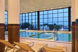 - une grande piscine avec des chaises et une table dans un bâtiment dans l'établissement Hôtel Barrière le Grand Hôtel Enghien-les-Bains, à Enghien-les-Bains