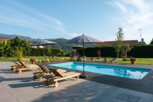 a swimming pool with lounge chairs and umbrellas at Casa Vieira Lobo in Arouca