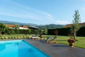 a swimming pool in a yard with chairs and an umbrella at Casa Vieira Lobo in Arouca