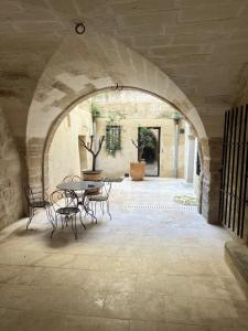 Un arco con una mesa y sillas en un patio en La Sapinière, en Uzès