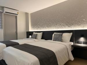 a bedroom with two beds and a wall at Lune bangkok in Bangna