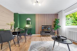 a living room with green walls and a table and chairs at Stylish 2BR Flat near Airport & Stadium, Sleeps 6 in Luton