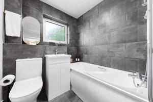 a bathroom with a white toilet and a sink and a tub at Stylish 2BR Flat near Airport & Stadium, Sleeps 6 in Luton +21 photos
