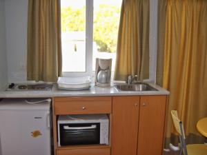 a kitchen with a sink and a microwave and a window at Fantasia Hotel Apartments in Kos Town