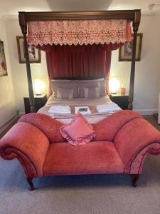 a bedroom with a large bed with a red couch at Parlors Hall Hotel in Bridgnorth