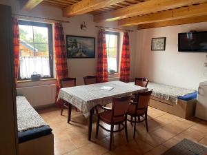 a dining room with a table and chairs and windows at Apartmány Diana in Lužice