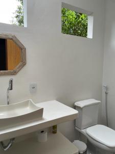 a white bathroom with a sink and a toilet at Canto do Sabiá Caraíva in Caraíva