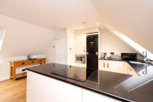 a kitchen with white cabinets and a black refrigerator at JOIVY Lovely Flats near the City Centre in Edinburgh
