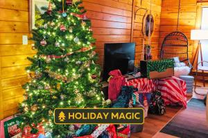 un árbol de Navidad en una sala de estar con un cartel mágico de vacaciones en Skypine Lodge - Log Lodge Atop the World, en Jim Thorpe