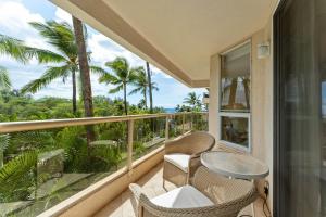 a balcony with a table and chairs and palm trees at Beautiful central kihei two bedroom (MBG309) in Wailea