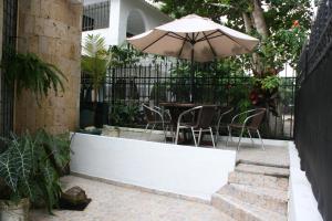 un patio con una mesa con sombrilla y sillas en Vivienda Turística El Castillo, en Buritaca