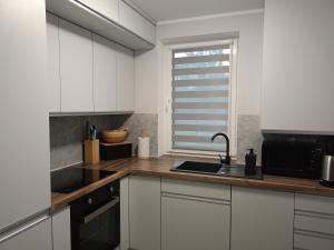 a kitchen with white cabinets and a sink and a window at U AGATKI -domek na wyłączność in Chełmno
