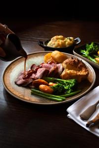 a plate of food with meat and vegetables on a table at Charingworth Manor in Chipping Campden