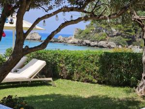 a white lounge chair under a tree next to the ocean at Corfu Dream Holidays Villas in Glyfada