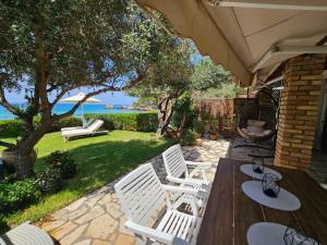 a patio with two white chairs and a wooden table at Corfu Dream Holidays Villas in Glyfada