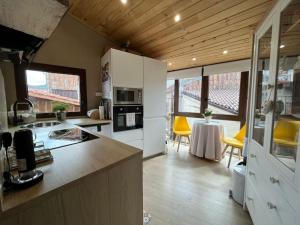 a kitchen with white cabinets and a table with yellow chairs at El Capricho de Rosa in Puerto de Béjar