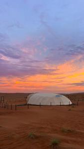 a tent in the middle of a desert with a sunset at La Duna Desert Camp in Shāhiq +39 photos