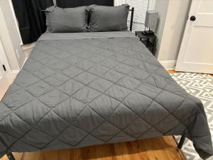 a bed with a gray comforter in a bedroom at HomeStay - B&B - Near South Boston - JFK-Umass Area in Boston