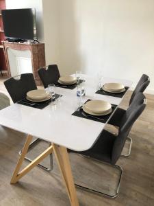 ボルドーにあるAppartement 1 Chambre au Cœur de Bordeauxの白いテーブル(椅子、皿、ワイングラス付)