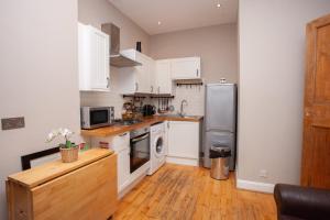 Una cocina con gabinetes blancos y un refrigerador de acero inoxidable. en Beautiful 2 Bed Apartment Rose St, en Glasgow