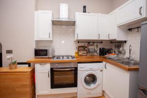 Una cocina con gabinetes blancos y lavadora. en Beautiful 2 Bed Apartment Rose St, en Glasgow 12 fotos más