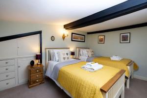 two beds in a bedroom with yellow sheets at Clematis Cottage Tealby LN8 3XU in Tealby