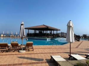 a swimming pool with two umbrellas and a pavilion at Sozopol Созопол- SOZOPOLIS -MORE SUN 2А- in Sozopol