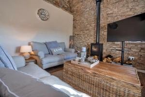 a living room with a couch and a tv at Finest Retreats - End Barn at Blackclough Farm in Buxton