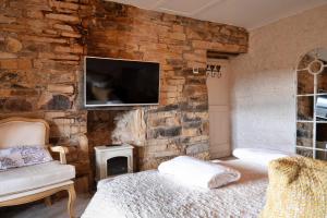 a bedroom with a stone wall with a bed and a tv at Finest Retreats - Blackclough Farmhouse at Blackclough Farm in Buxton