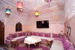 a room with purple furniture and a tv on a wall at Hostel Essassi 23 in Marrakesh