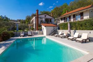 a swimming pool with chairs and a house at SROK luxury apartments by the pool in Kastav