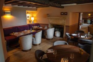 a restaurant with tables and chairs and a fireplace at Charingworth Manor in Chipping Campden